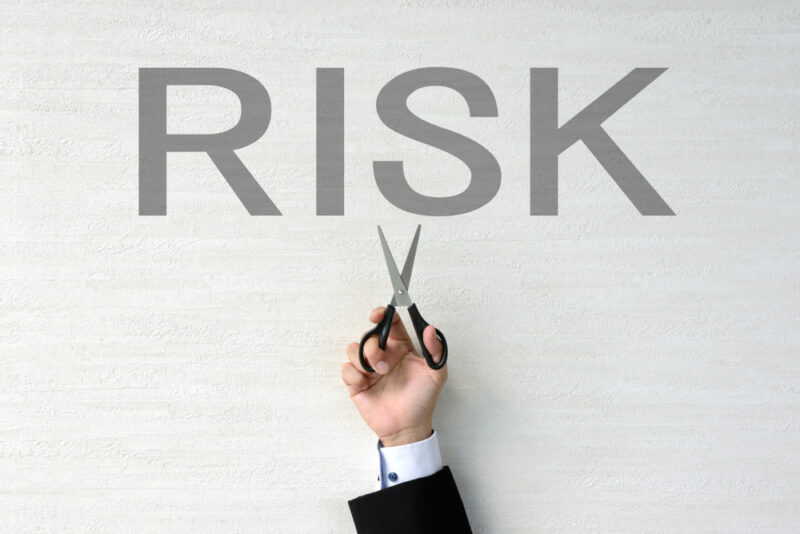 RISKという文字にハサミを入れようとしているビジネスマン